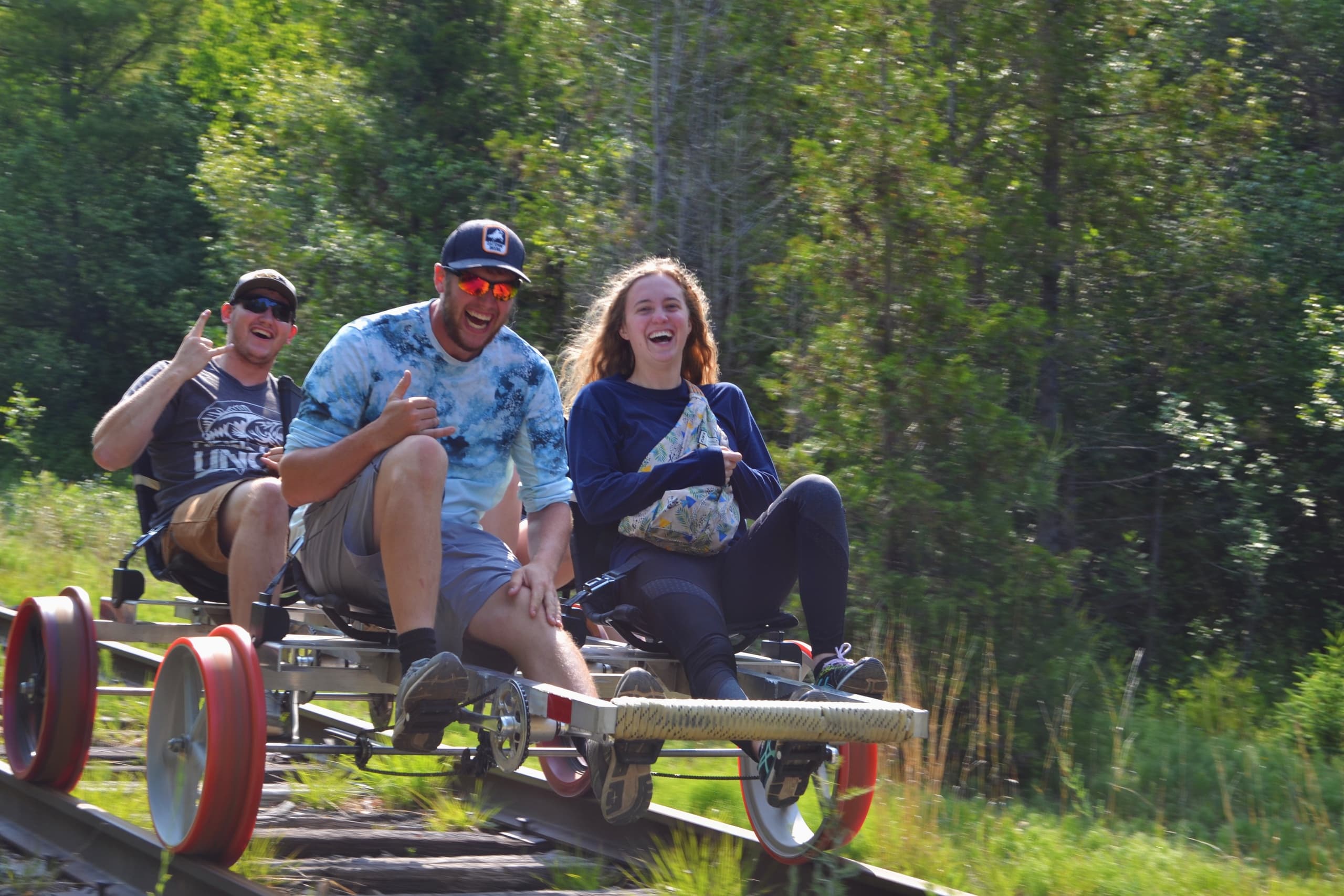 Friends riding pedal rail carts on scenic forest railway trail