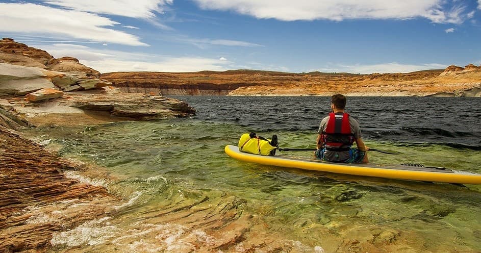 Solo kayaker paddling through red-rock canyon, scenic river route