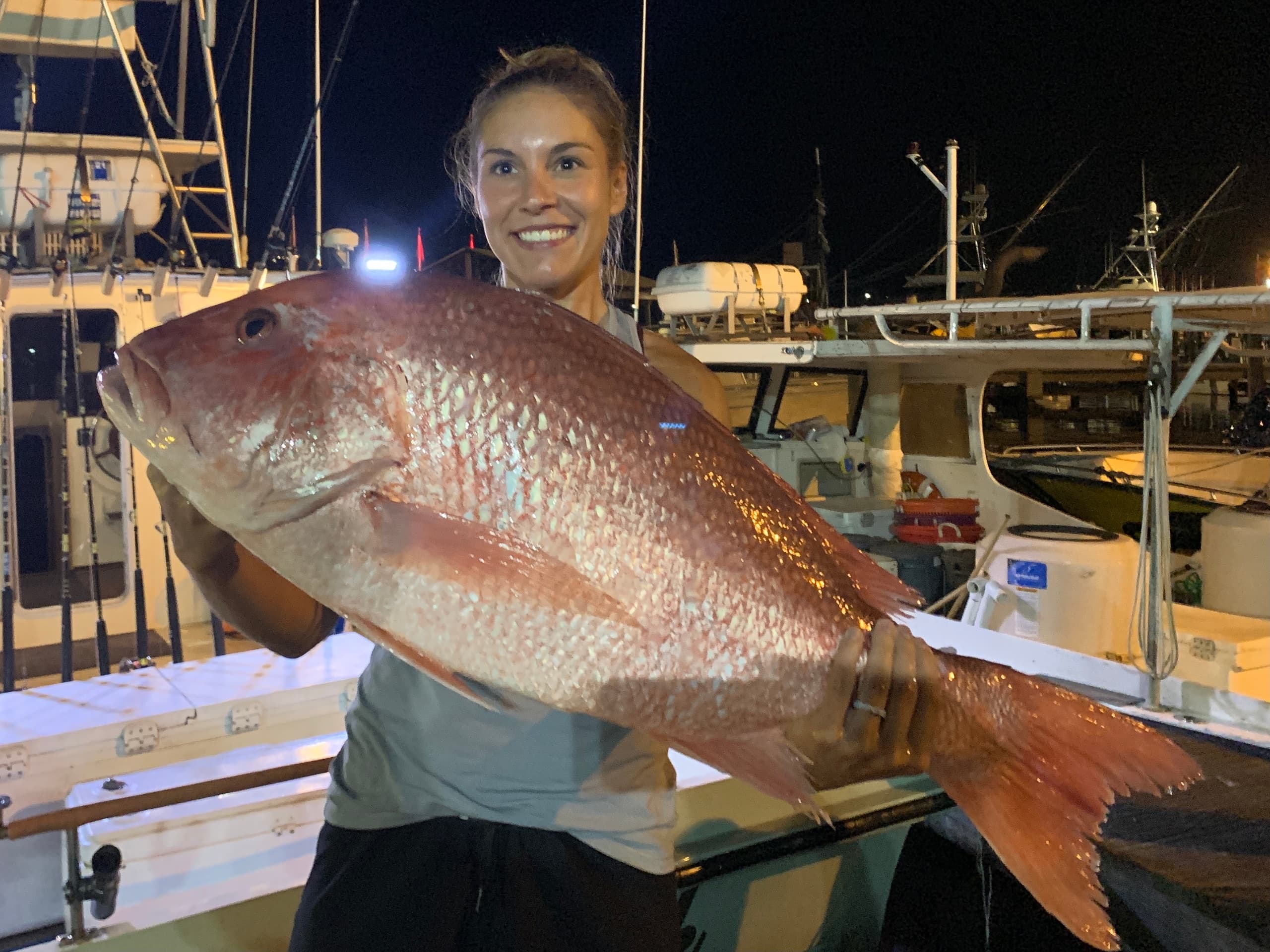 Angler holding giant snapper on boat at night fishing charter