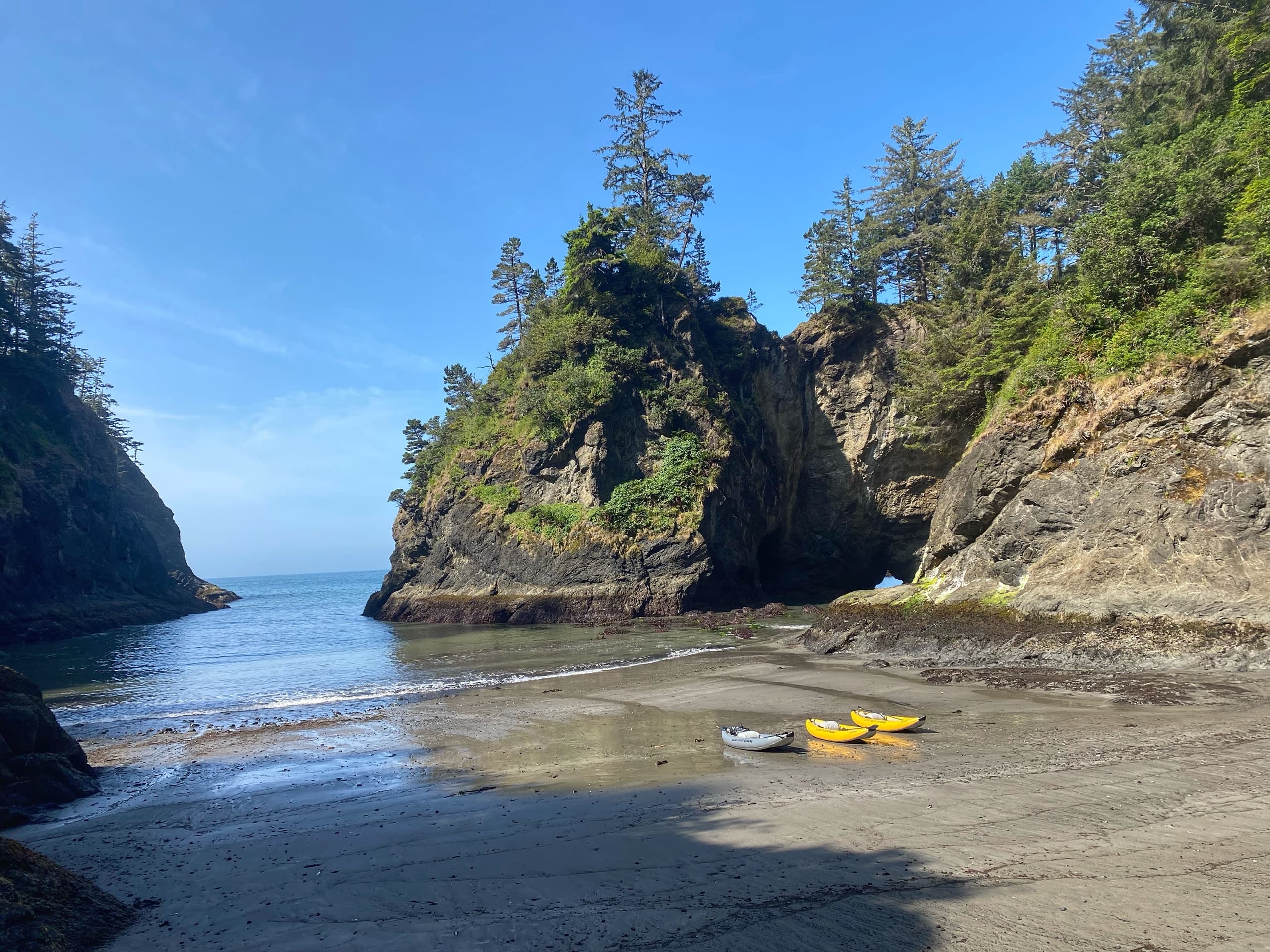 Two kayaks on a secluded rocky beach cove under blue sky