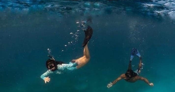 Snorkelers swimming under clear Caribbean waters near reef