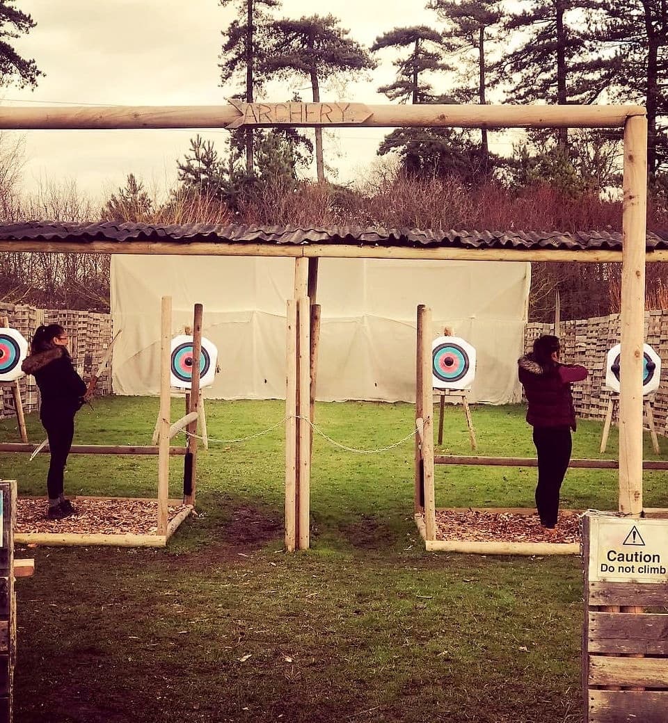 Outdoor archery lane with instructors and targets on grass