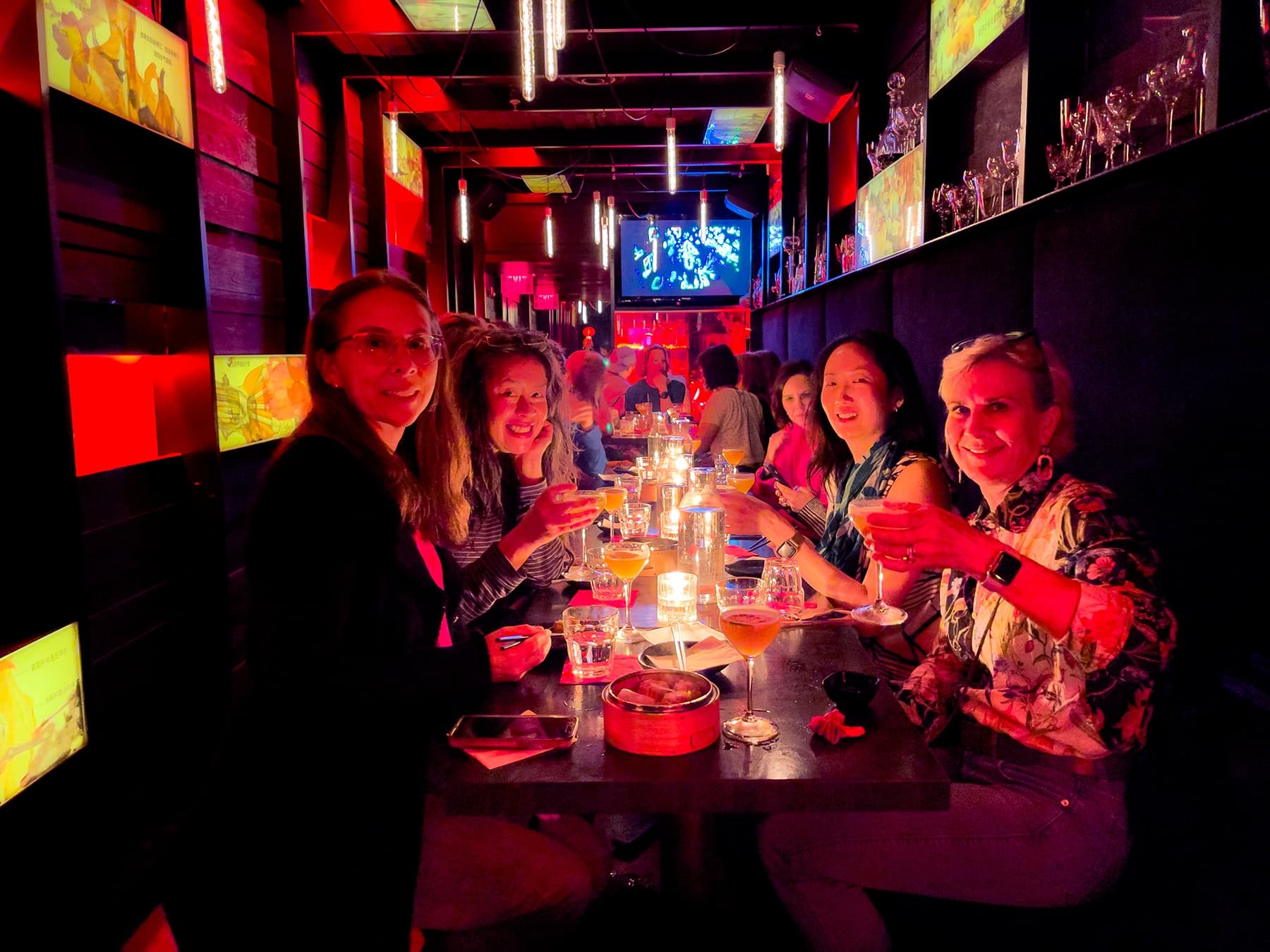 Friends toasting drinks at intimate neon-lit Chinatown supper club