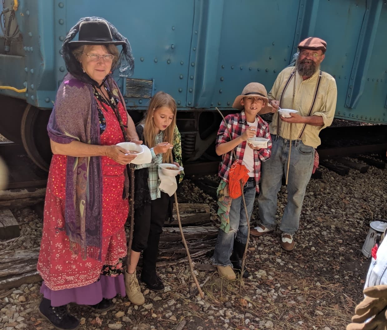 Living history reenactors in period clothing beside vintage train