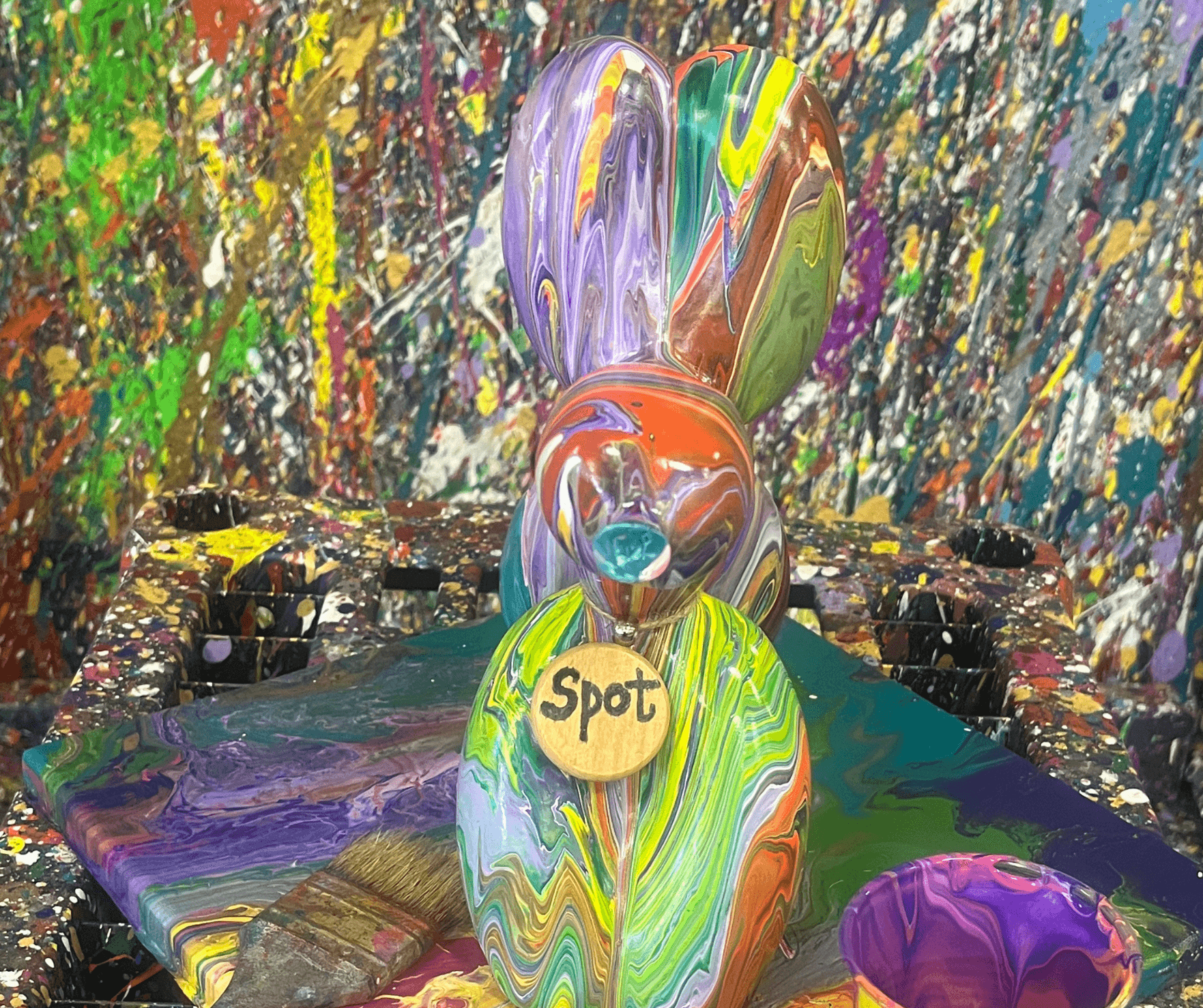 Colorful poured-paint sculpture bunny on splattered studio table