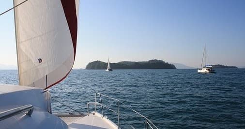 Sailboat deck cruising past islands on open ocean in Hawaii