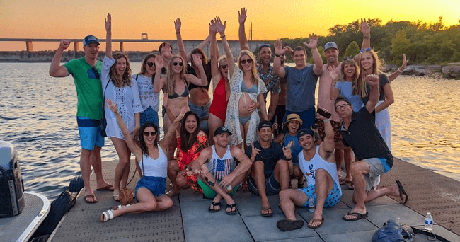Group of friends posing on dock at sunset during lake party