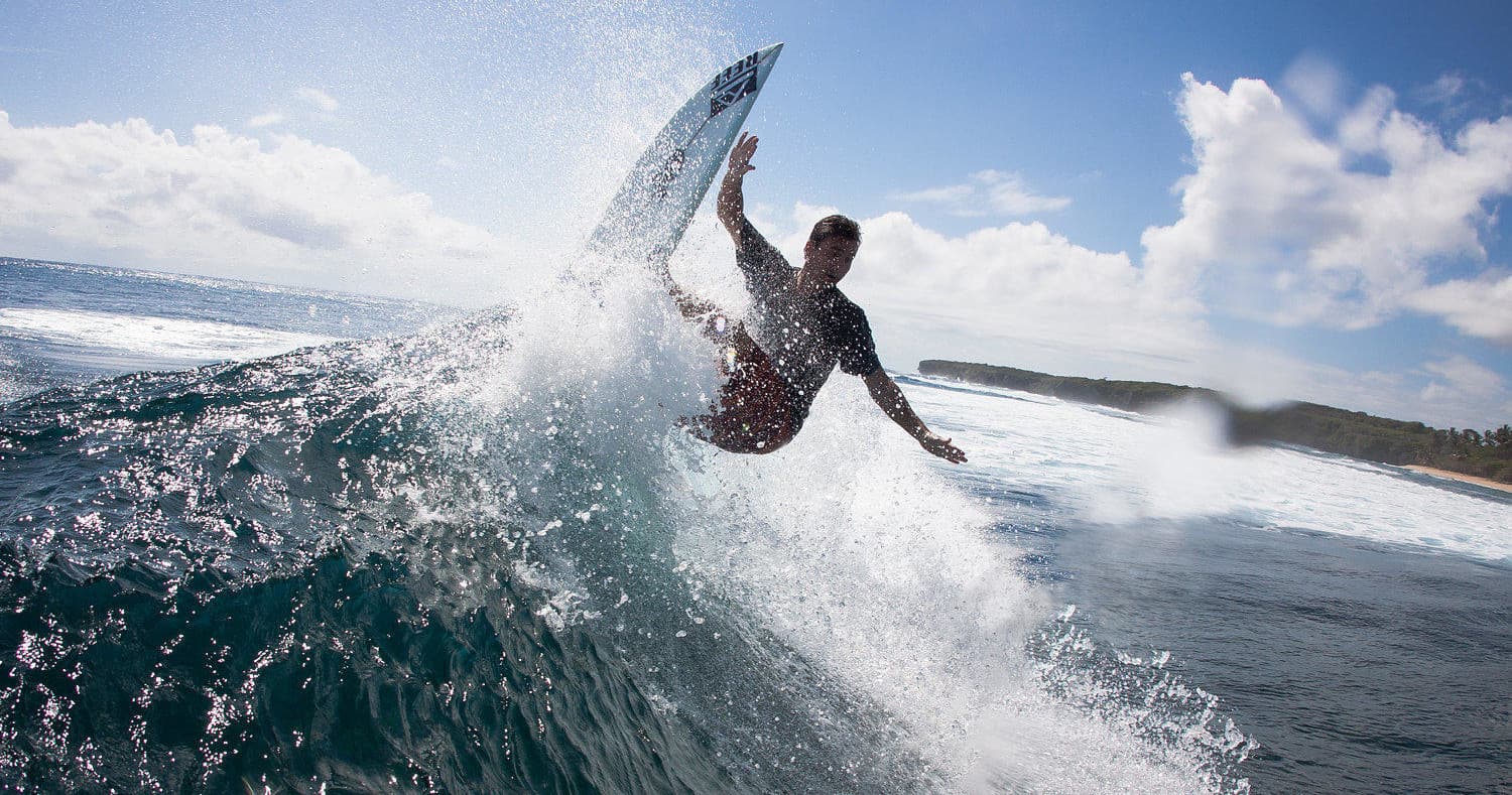 Surfer carving wave spray offshore in dynamic action shot