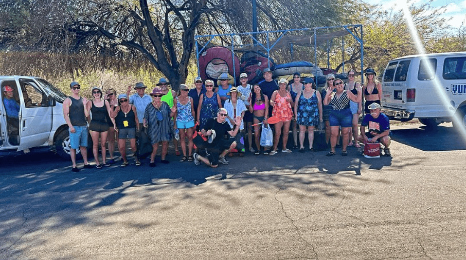Large rafting group staged by vans in parking area near river launch
