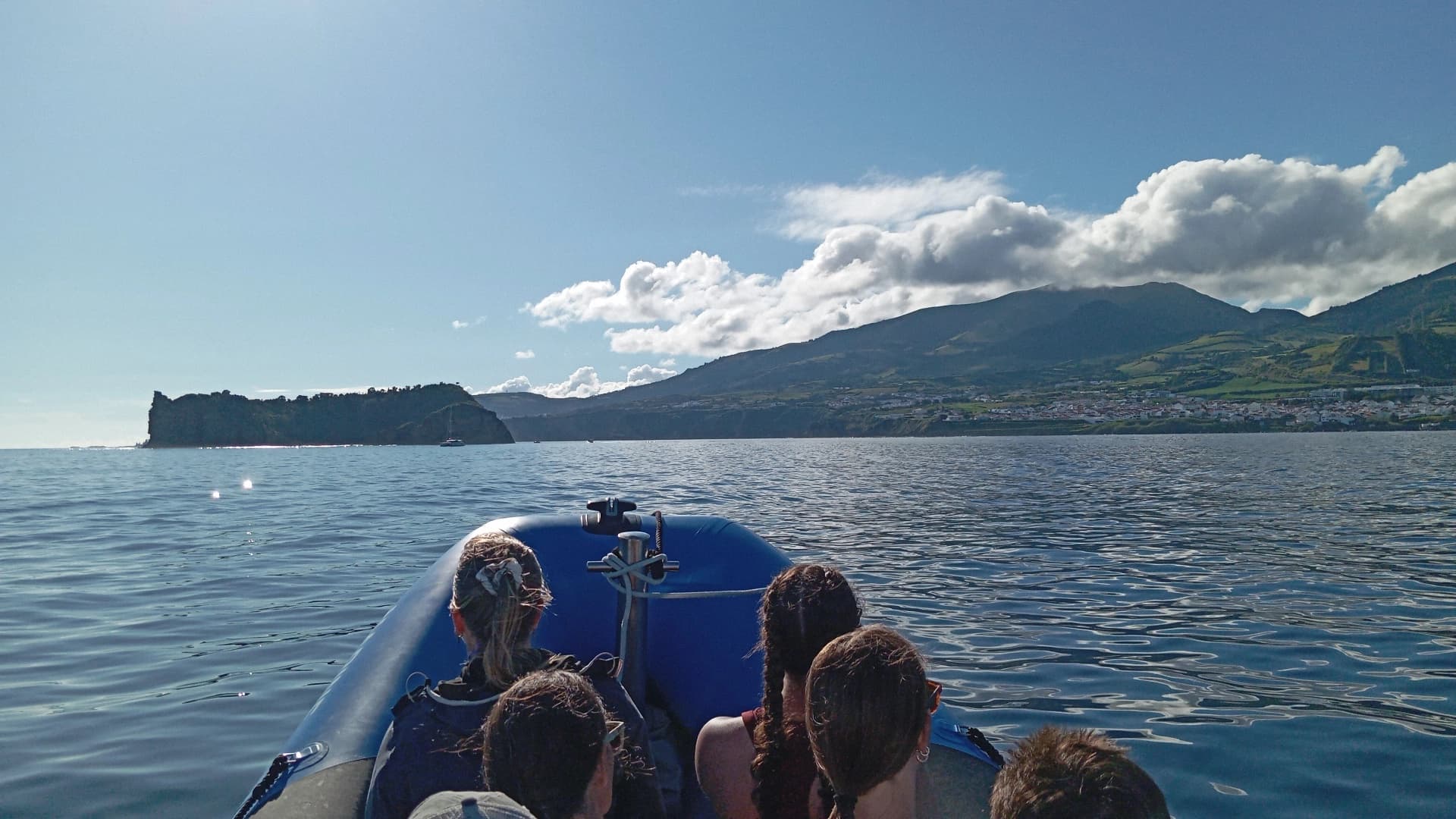 Passengers enjoying rigid-hull boat tour near sea cliffs and coast