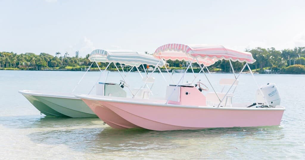 Two pastel boats anchored in calm coastal waters under sun