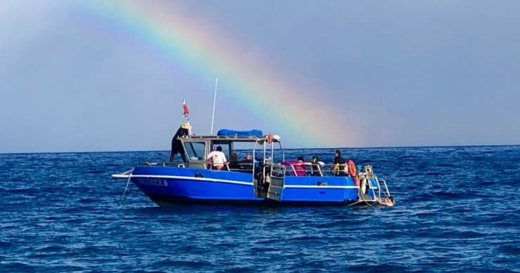 Blue dive boat under rainbow on Maui coast during ocean excursion