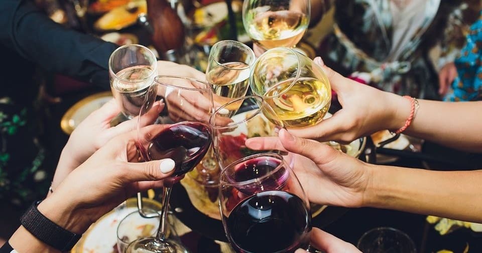 Friends clinking wine glasses at indoor dinner party gathering