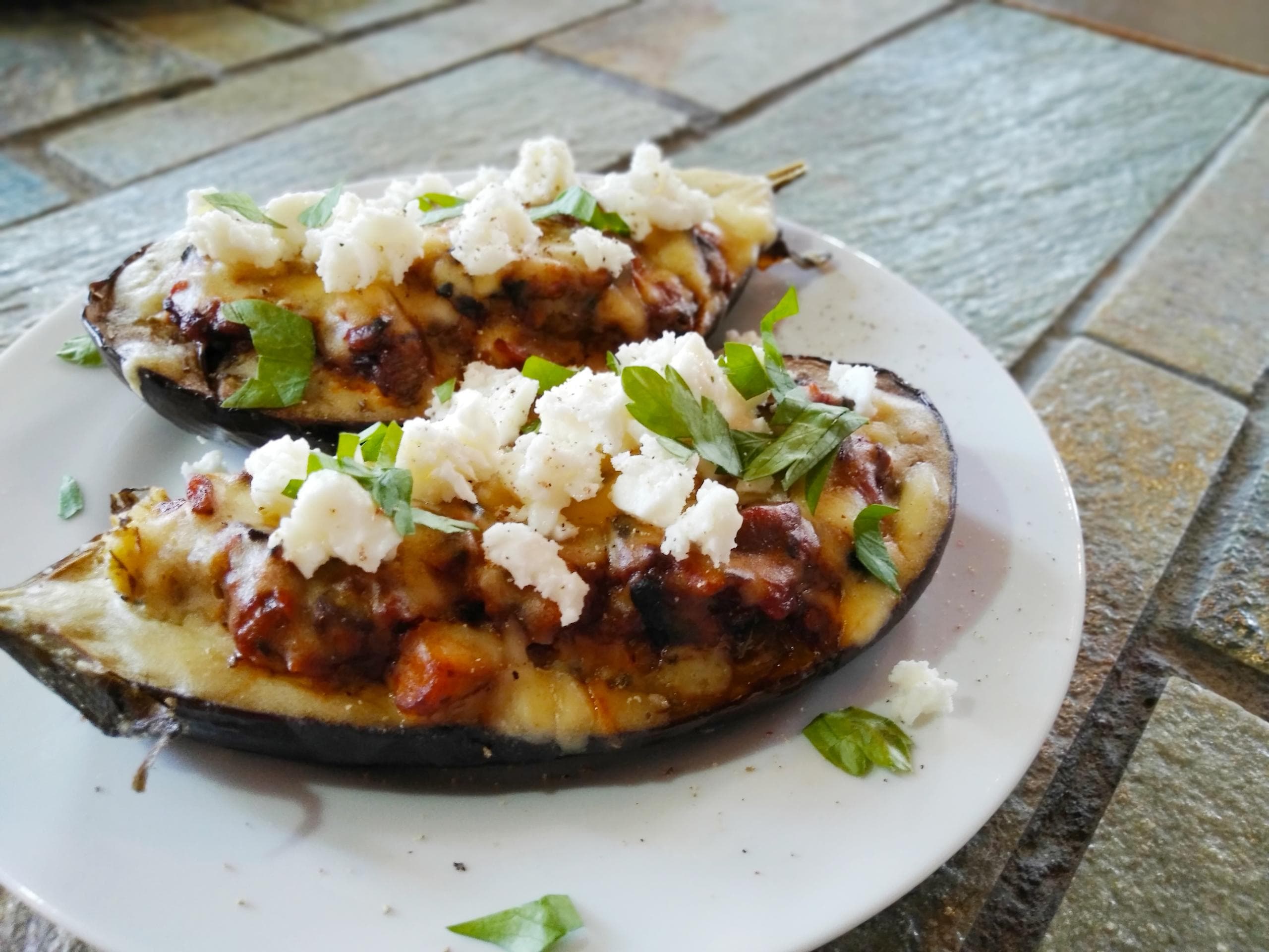 Grilled eggplant with feta on rustic outdoor stone tabletop