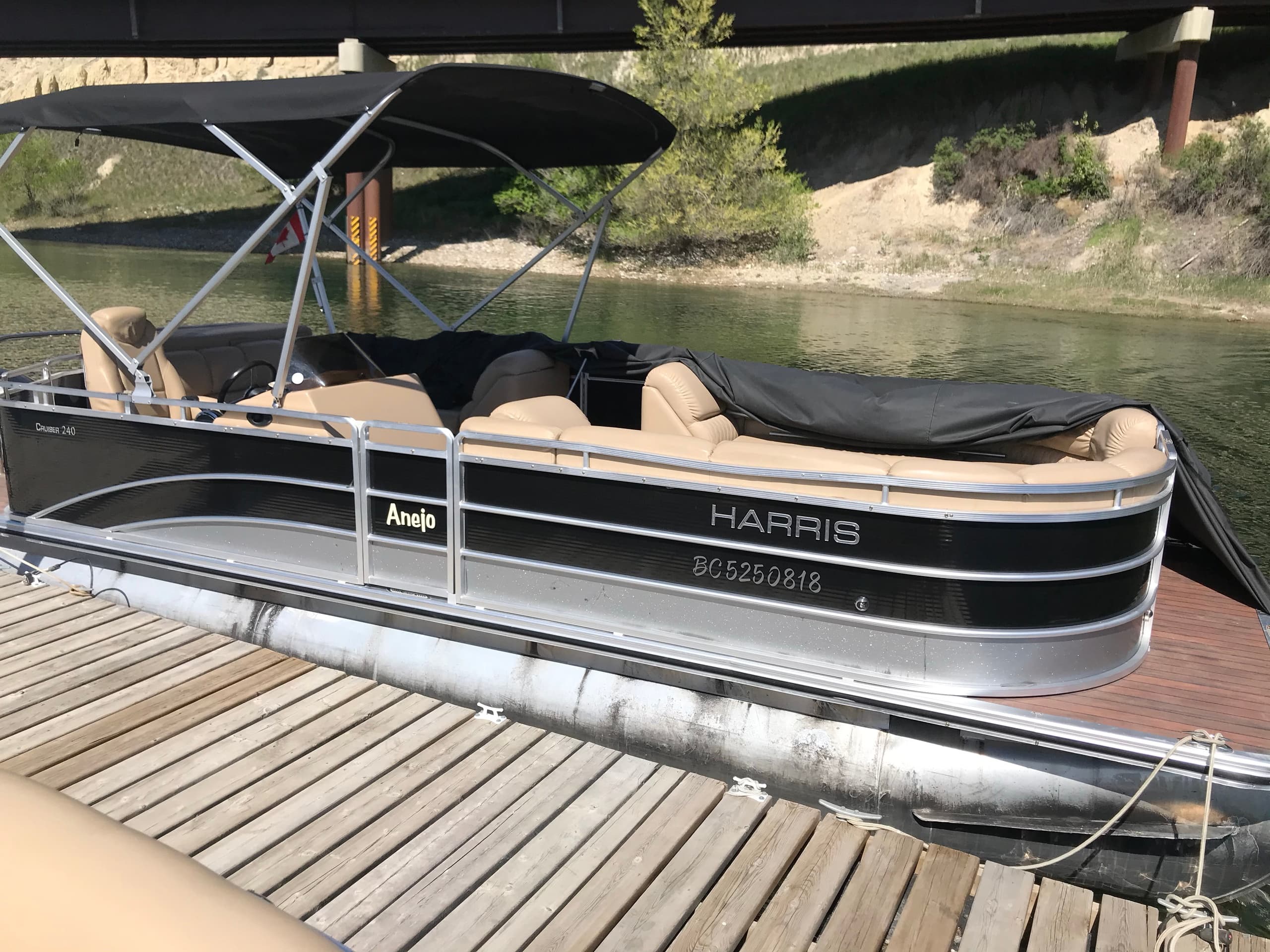 Black Harris pontoon at dock with canopy, calm waters