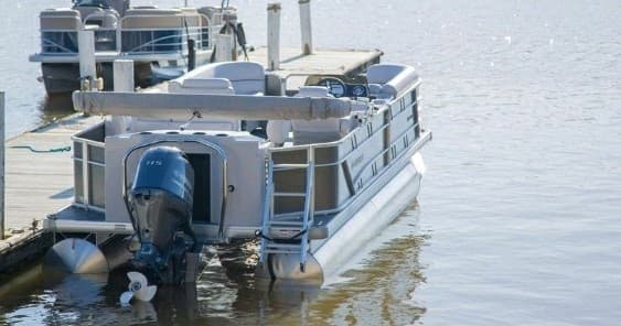 Pontoon boat docked on calm lake at marina for leisure cruise