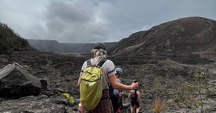 Hikers overlooking volcanic crater rim on rugged lava field