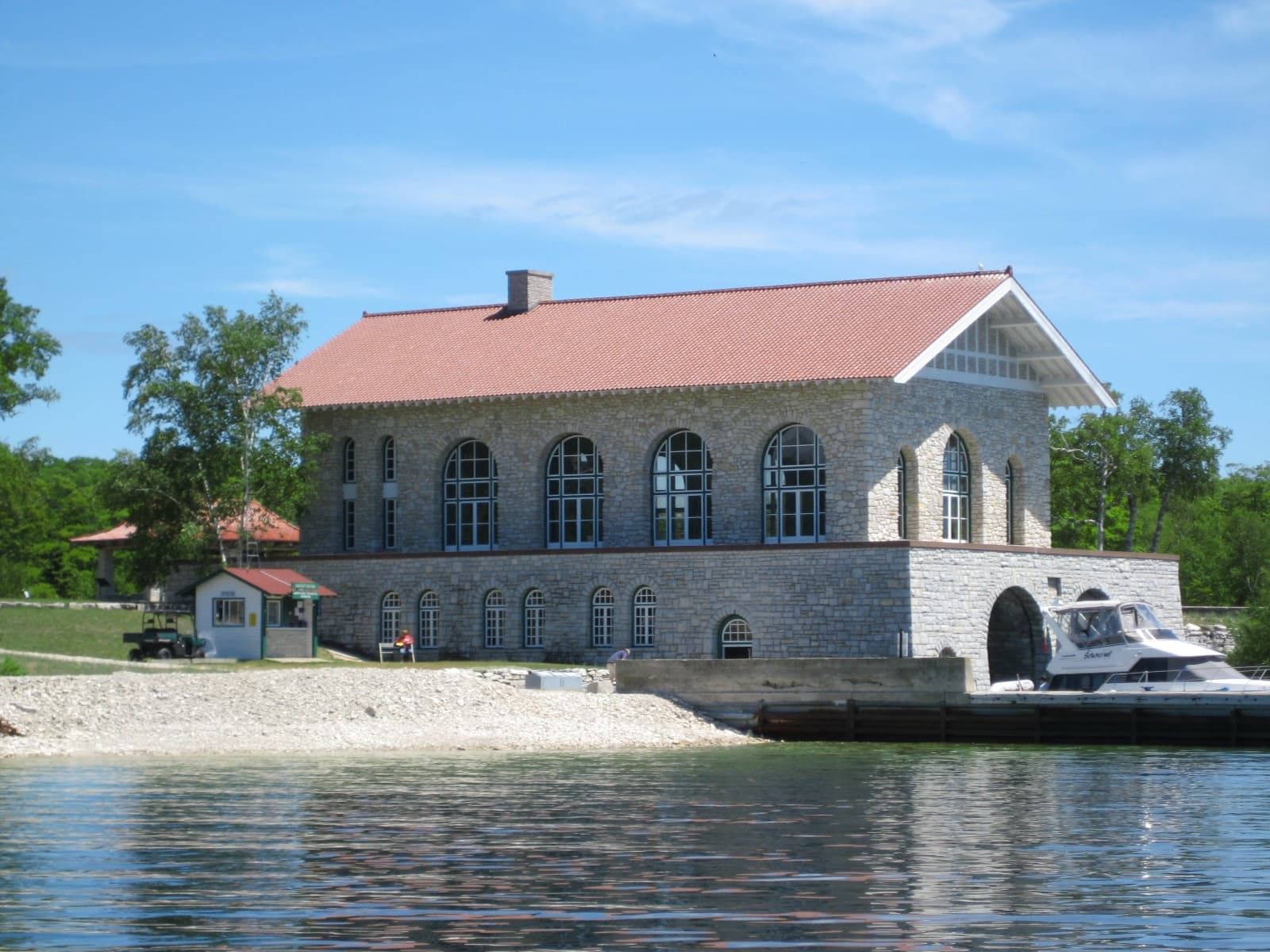 Stone boathouse on serene lakefront with bright summer sky