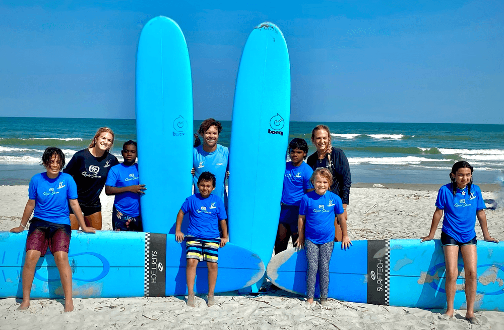 Youth surf lesson on sandy beach with instructors and boards