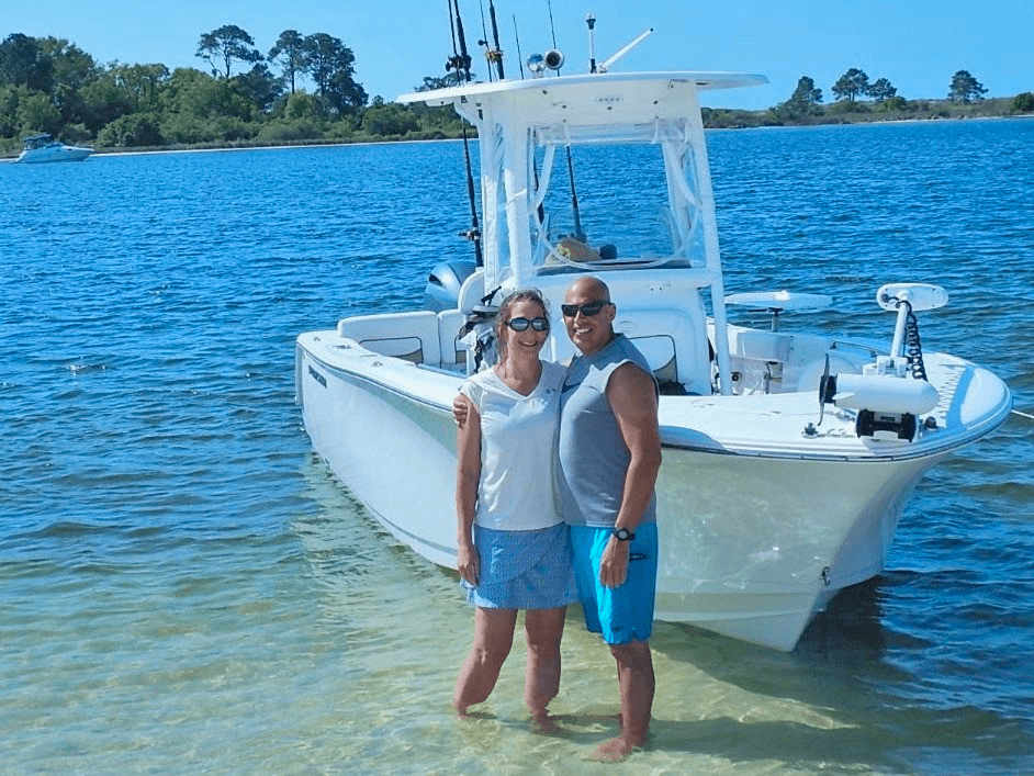Couple standing by a sportfishing boat in shallow coastal water