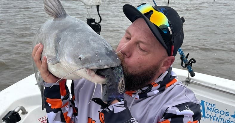 Angler kissing large catfish on inshore river fishing boat