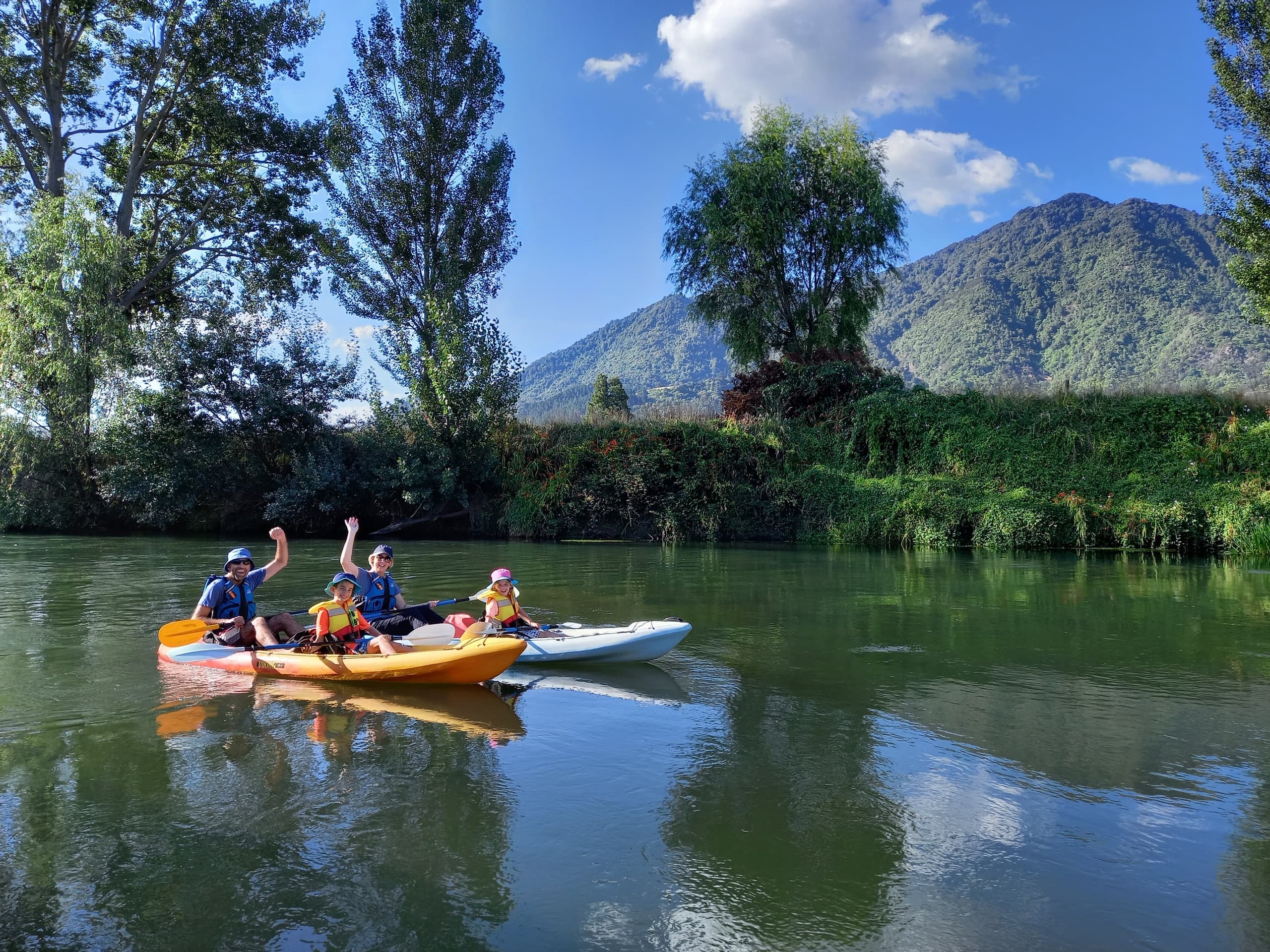 Group kayaking on calm river with mountains and trees backdrop