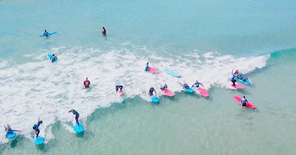 Aerial shot of surfers riding waves in turquoise coastal surf