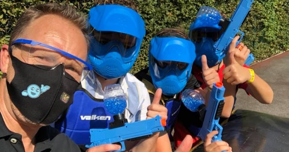 Players posing with blue laser tag gear outdoors before game