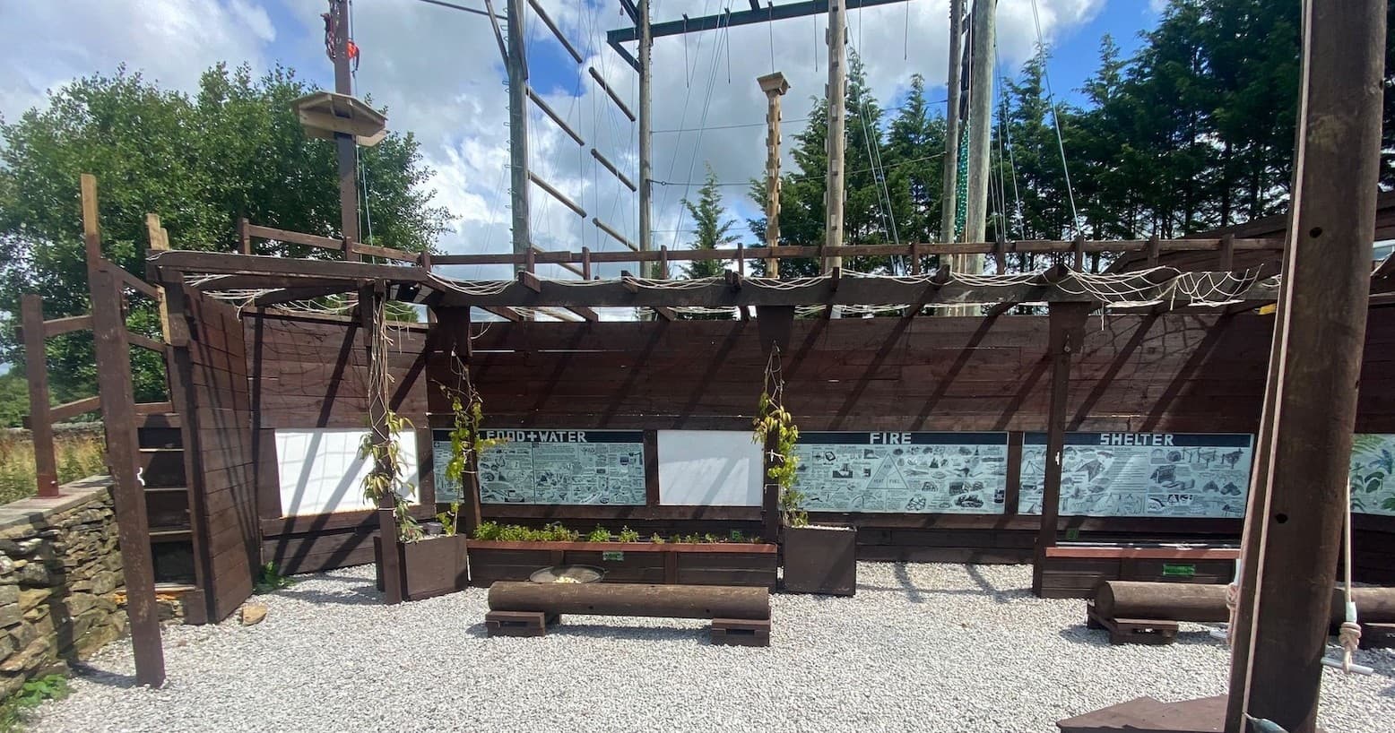 Wooden outdoor adventure base area with benches and climbing frames