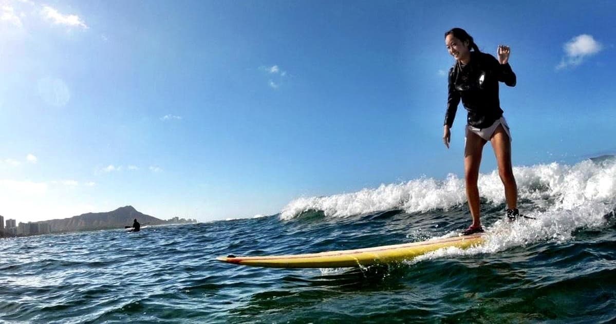 Surfer riding a wave on a yellow board in sunny ocean coastal beach