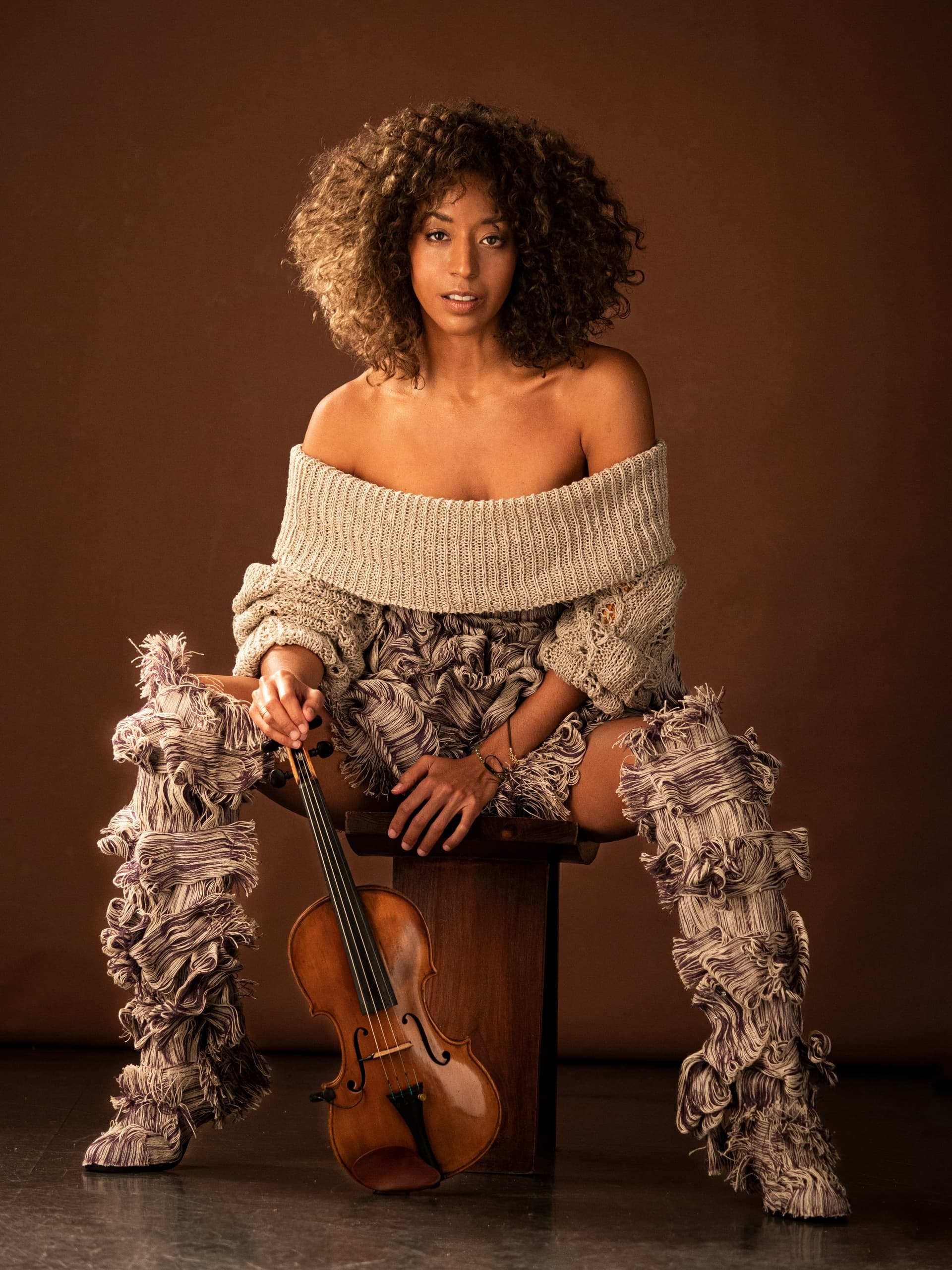 Violinist portrait seated in studio wearing textured outfit