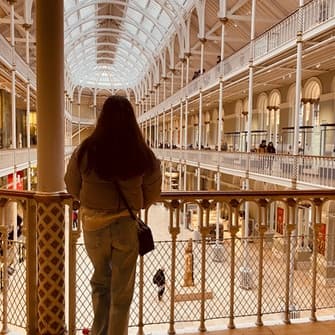 Person standing on museum balcony overlooking grand atrium interior