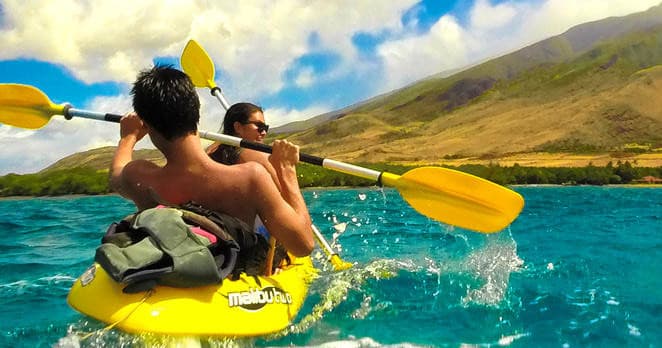 Two paddlers in yellow kayak speeding across turquoise Maui waters