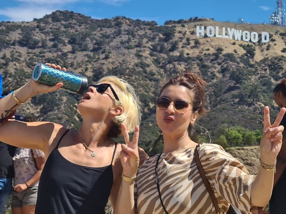 Tourists posing near the Hollywood Sign at sunny hillside viewpoint