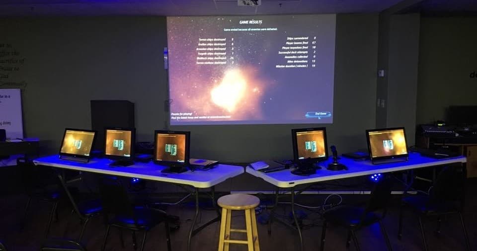 Empty projection gaming lab setup with multiple PCs indoors
