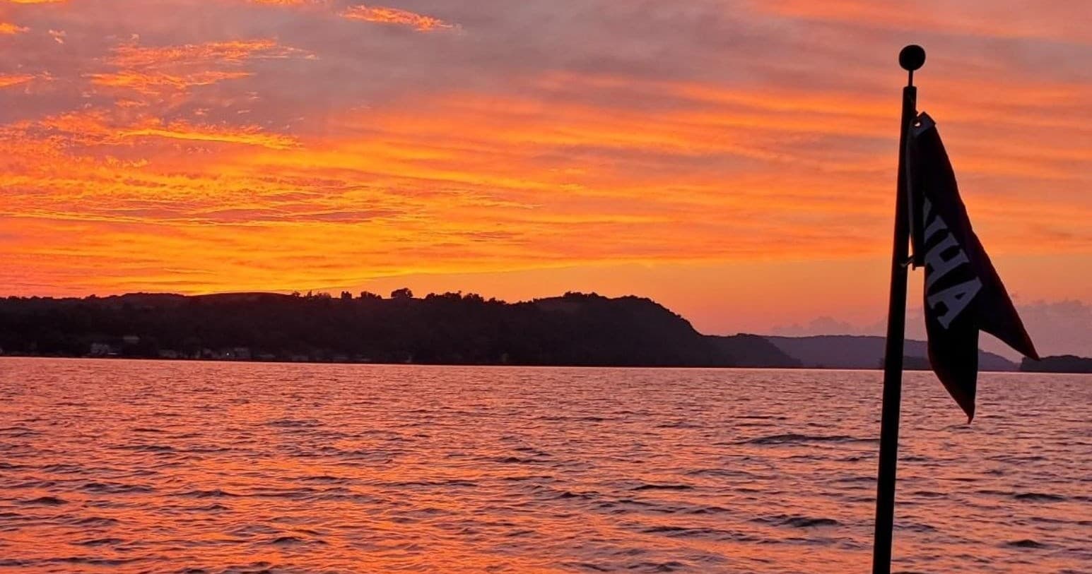 Sunset cruise view over Susquehanna River with flag on stern