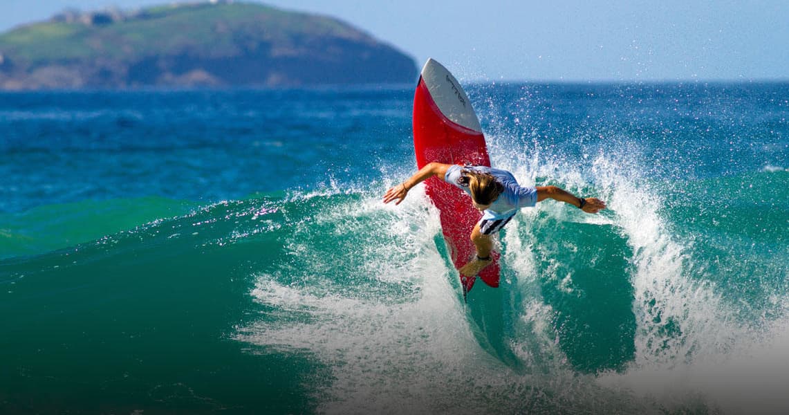 Surfer carving a large wave off a rocky coastal break
