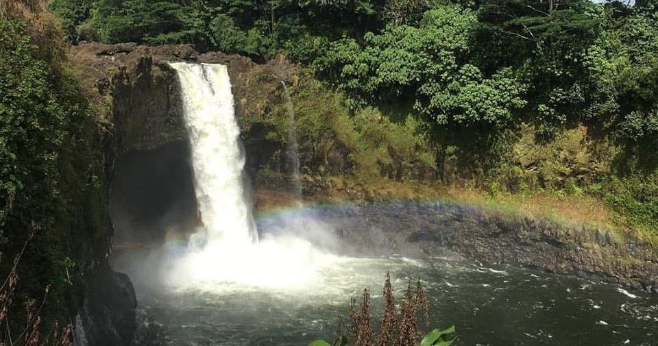Lush waterfall plunging into pool with rainbow, tropical forest, Hawaii