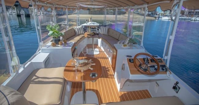 Wooden deck boat interior with seating and clear ocean harbor views