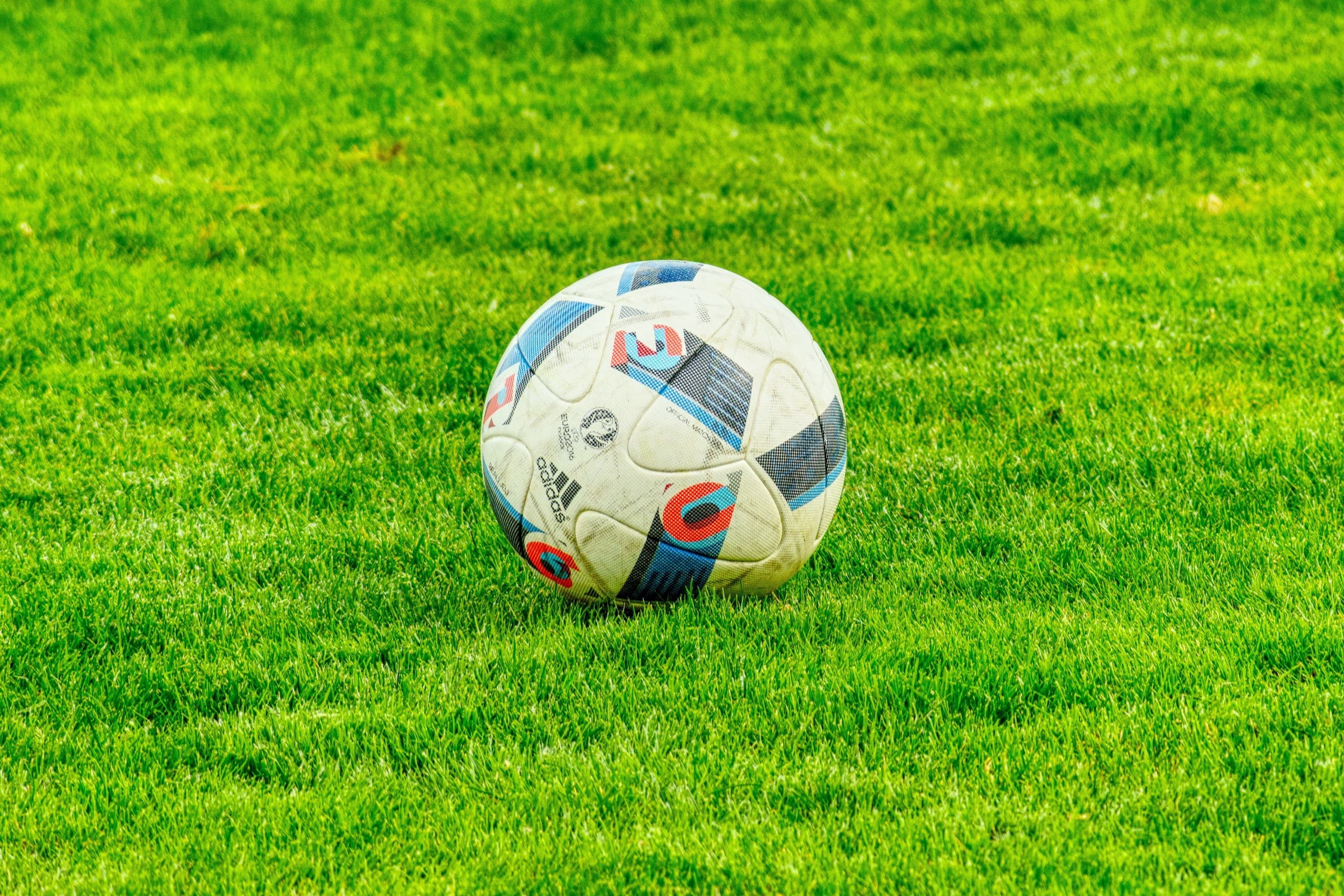 Soccer ball resting on vibrant green grass at outdoor field