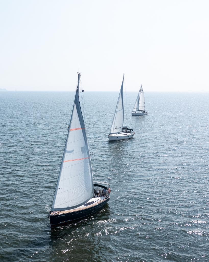 Aerial view of multiple sailboats racing across open ocean