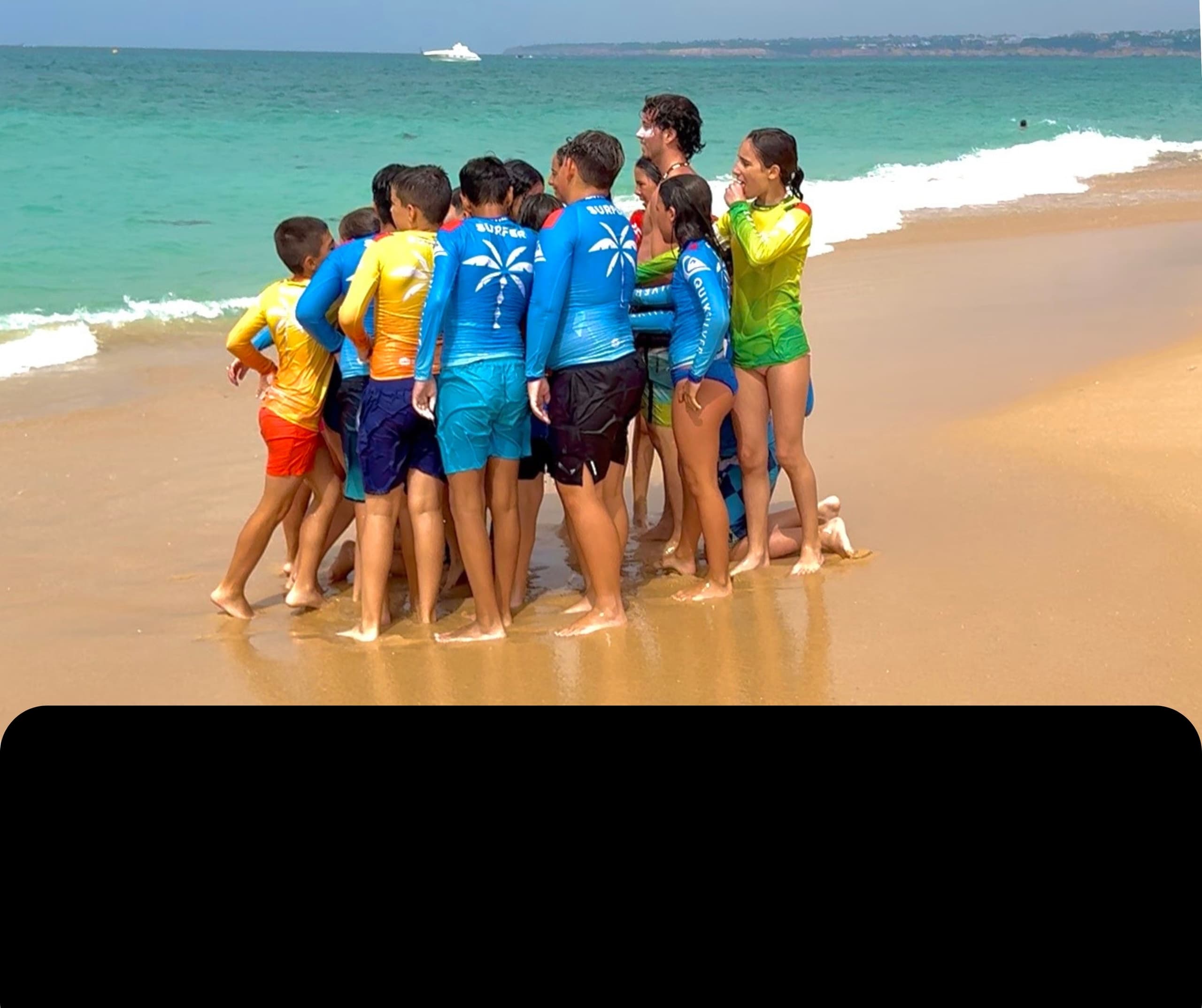 Kids surf school huddle on warm sandy beach before lesson