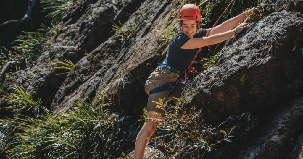 Climber scaling steep rock face on guided outdoor climb
