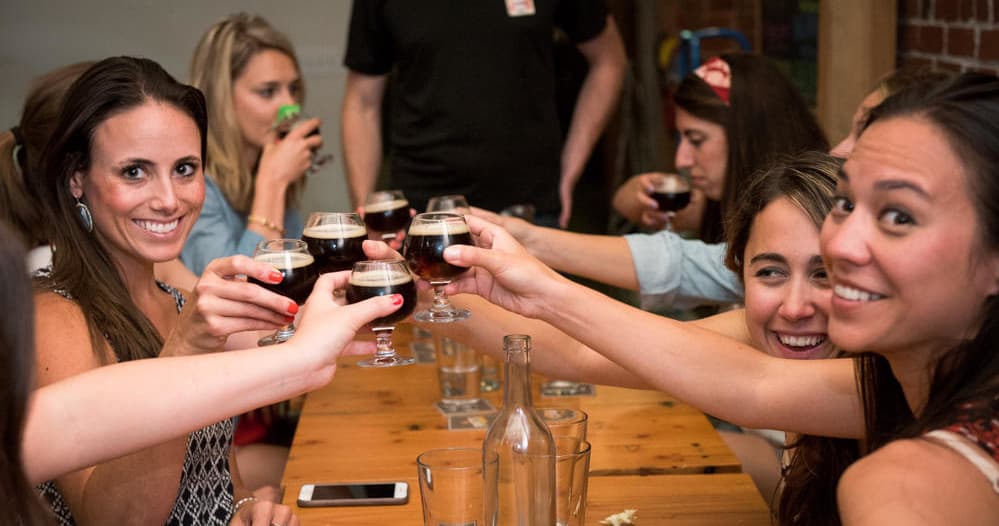 Friends clinking craft beer glasses at a Portland brewery tasting table