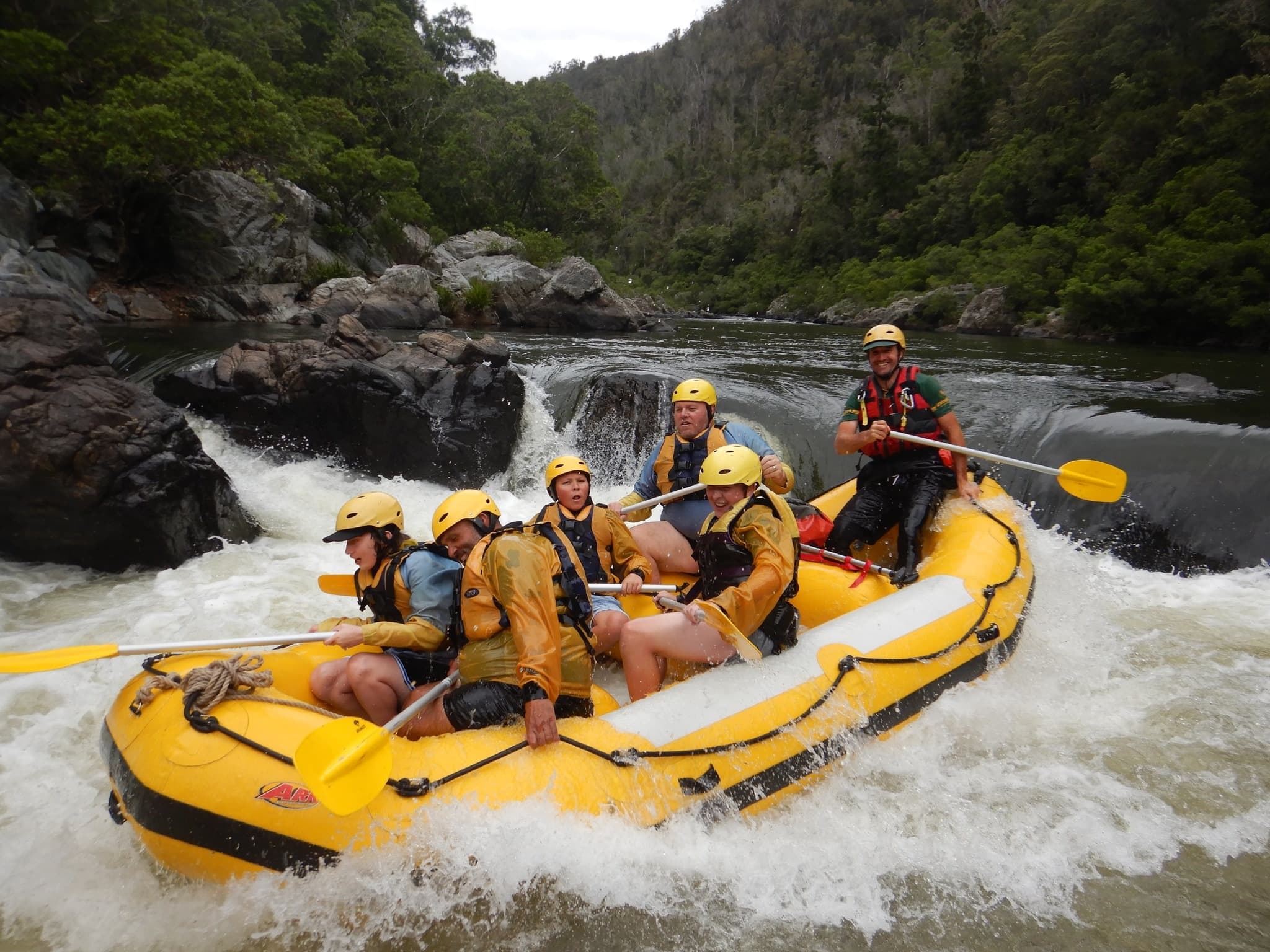 Guided whitewater rafting crew paddling through rocky gorge rapids
