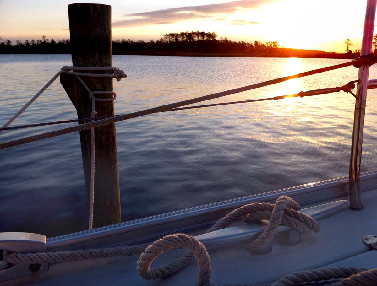 Sunset over marina with mooring lines and wooden post