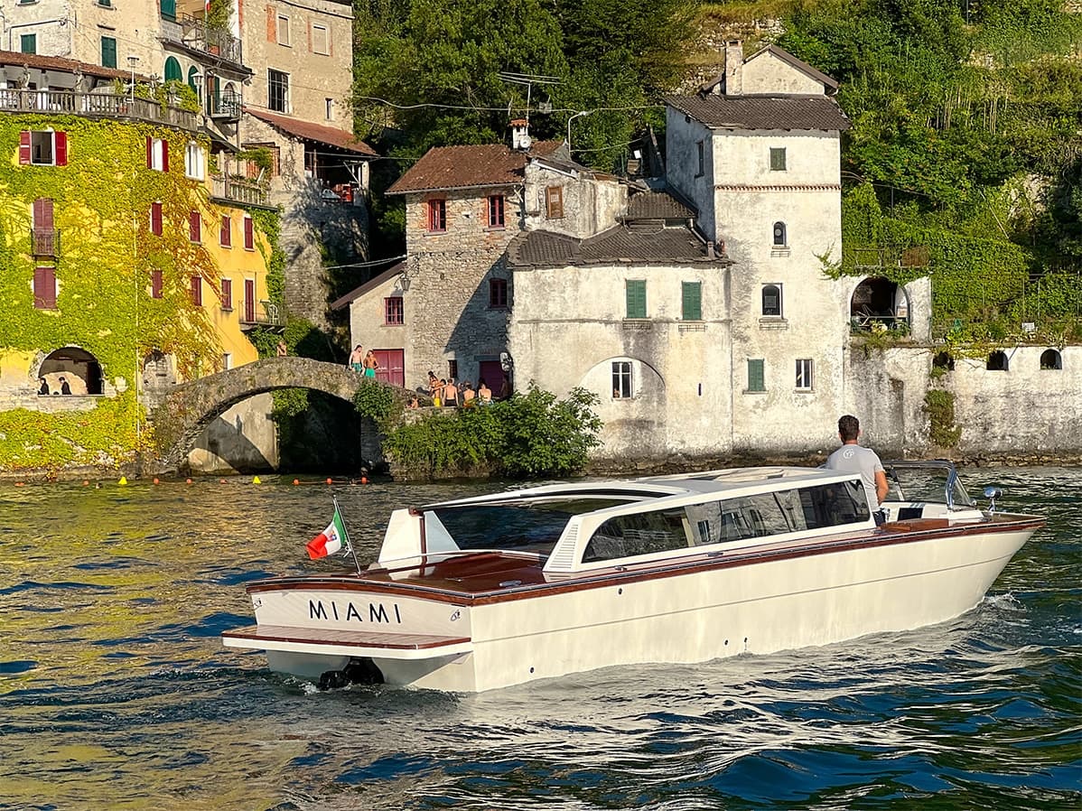 Private powerboat cruising past historic lakeside village on clear day