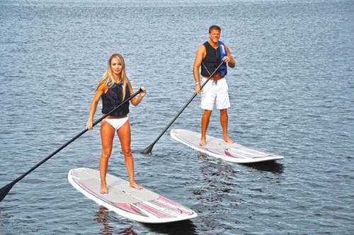 Man and woman stand-up paddleboarding together on calm lake