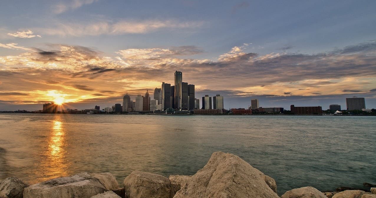 Sunset skyline view across Detroit River with rocky foreground