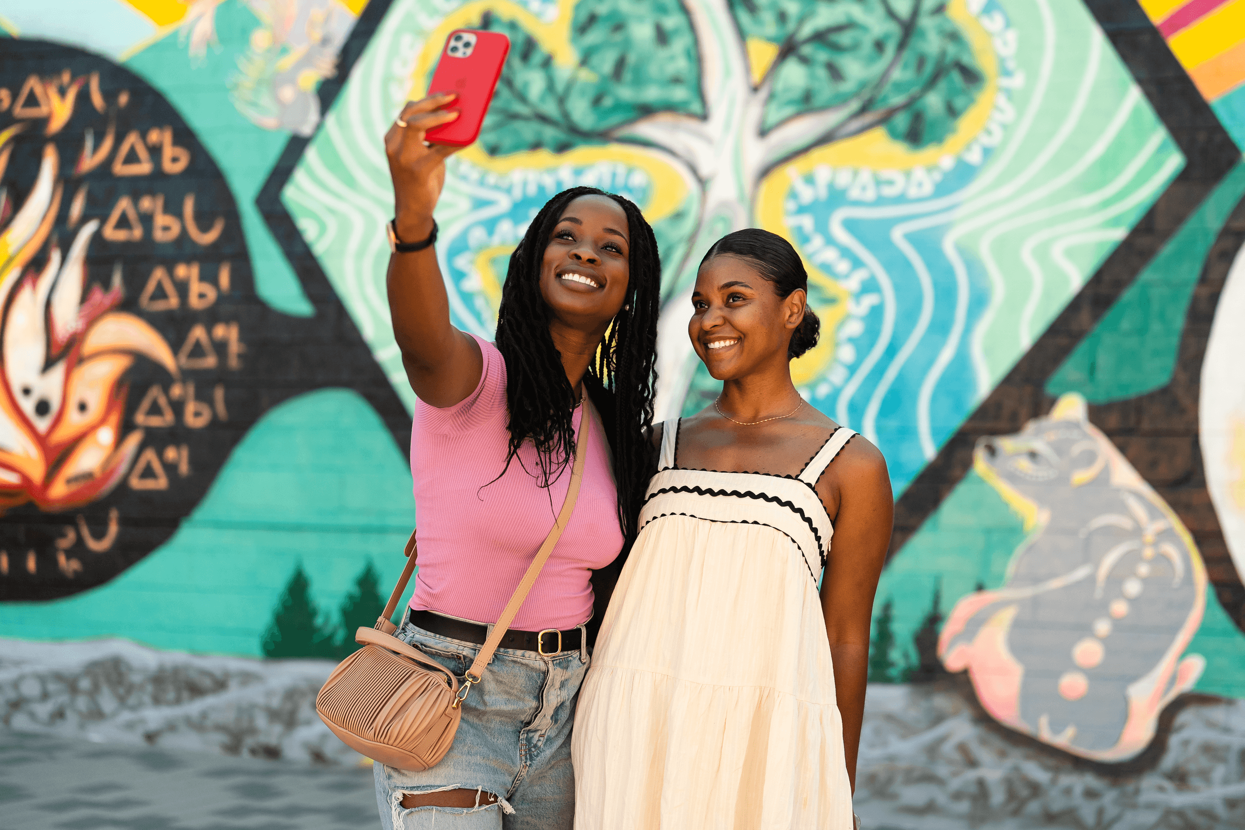 Friends taking selfie before colorful street mural in city
